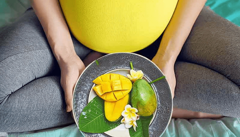 gravida sentada com um prato de frutas