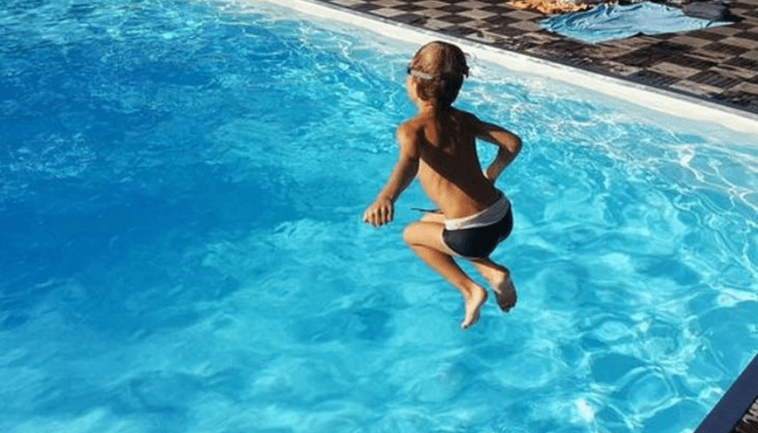 Criança pulando na piscina